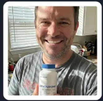 satisfied male customer holding DentaBiome oral probiotic supplement bottle and smiling at home